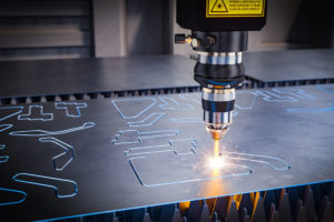 A CNC laser cutting out shapes in a metal board